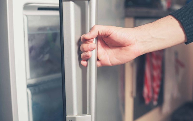 33455170 - the hand of a young man is opening a freezer door