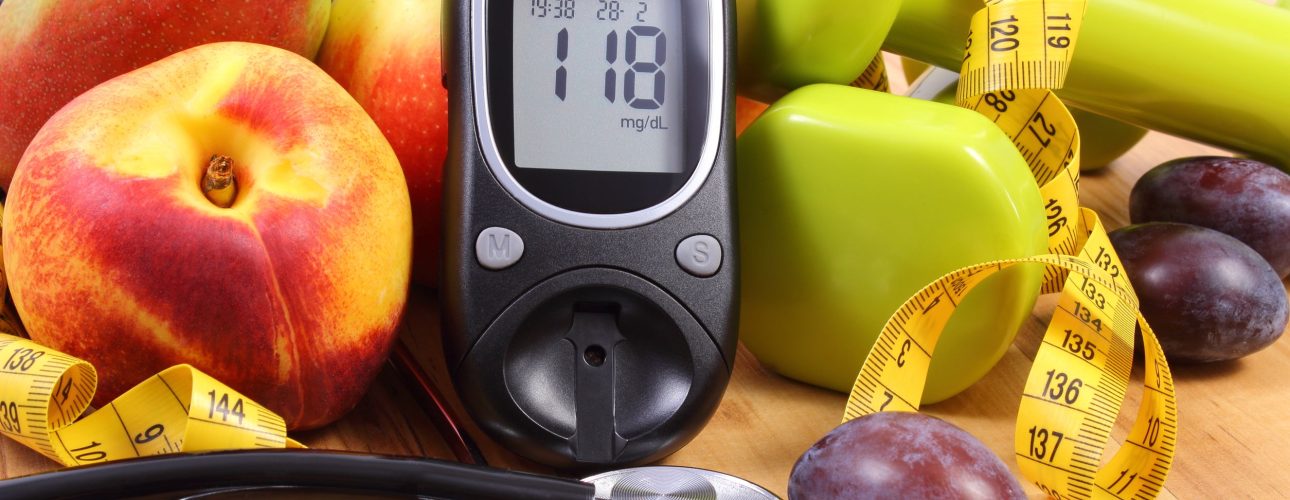 Glucose meter with medical stethoscope, fruits and dumbbells for using in fitness, concept of diabetes, healthy lifestyles and nutrition