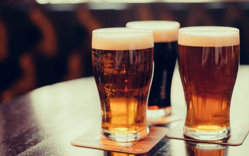 Glasses of light and dark beer on a pub background.