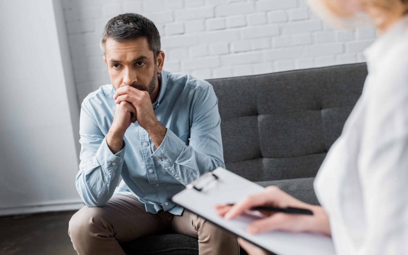 depressed adult man on psychologist therapy session at office