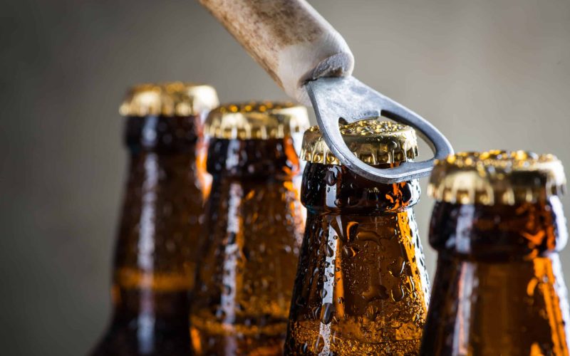 Brown ice cold beer bottles with water drops and old opener