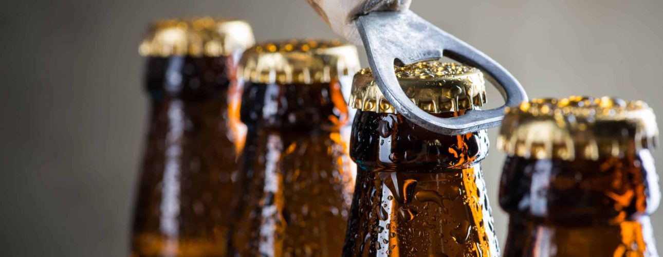 Brown ice cold beer bottles with water drops and old opener