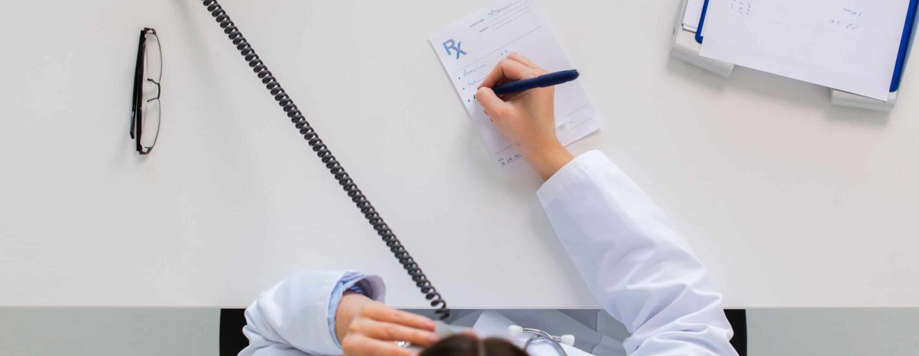 medicine, healthcare and people concept - doctor with prescription calling on phone at table in clinic