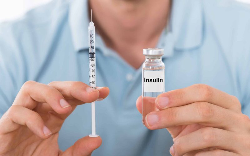 Close-up Of Young Man Holding Insulin And Syringe