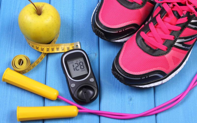 Glucose meter with result of sugar level, sport shoes, apple and accessories for fitness or sport, diabetes, healthy and active lifestyles