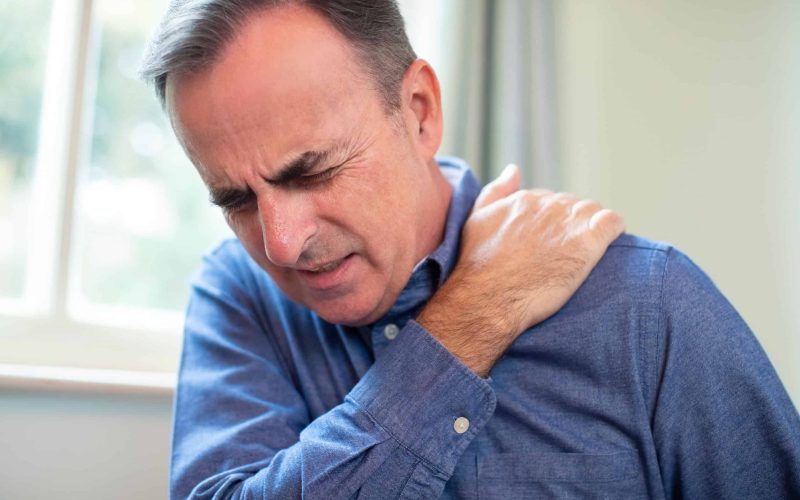 Mature Man Suffering With Trapped Nerve In Shoulder At Home