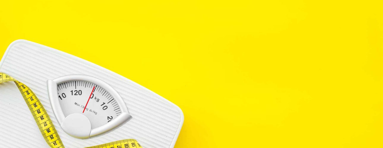 Diet. Bathroom scales and measuring tape for weight loss concept on yellow background top view mock up