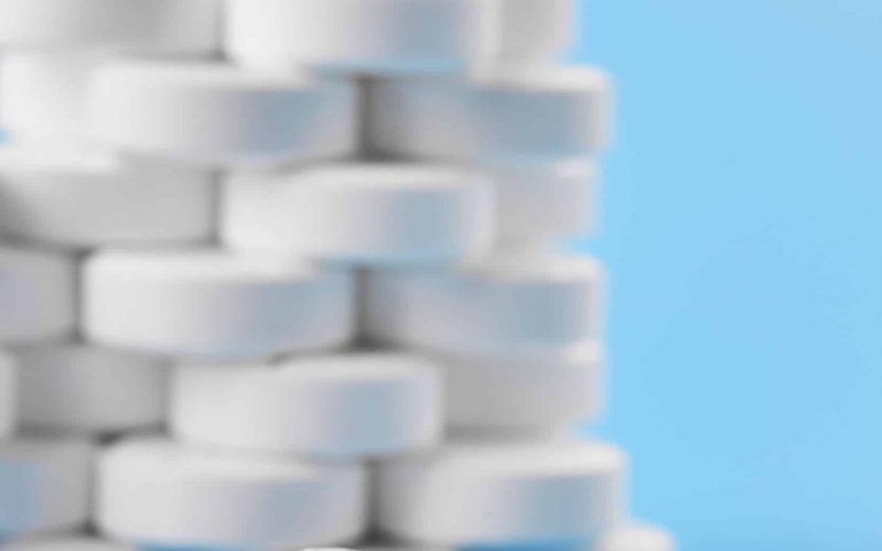 Pills tablets capsules closeup. On a blue background, a jar of medicine. White pills on the background