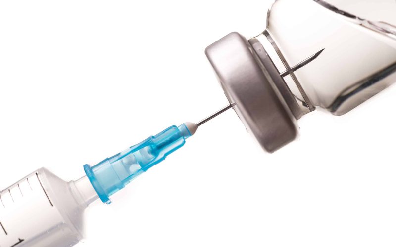 Syringe, needle and medicine vial. The needle sticks through the sterile membrane into the clear liquid.