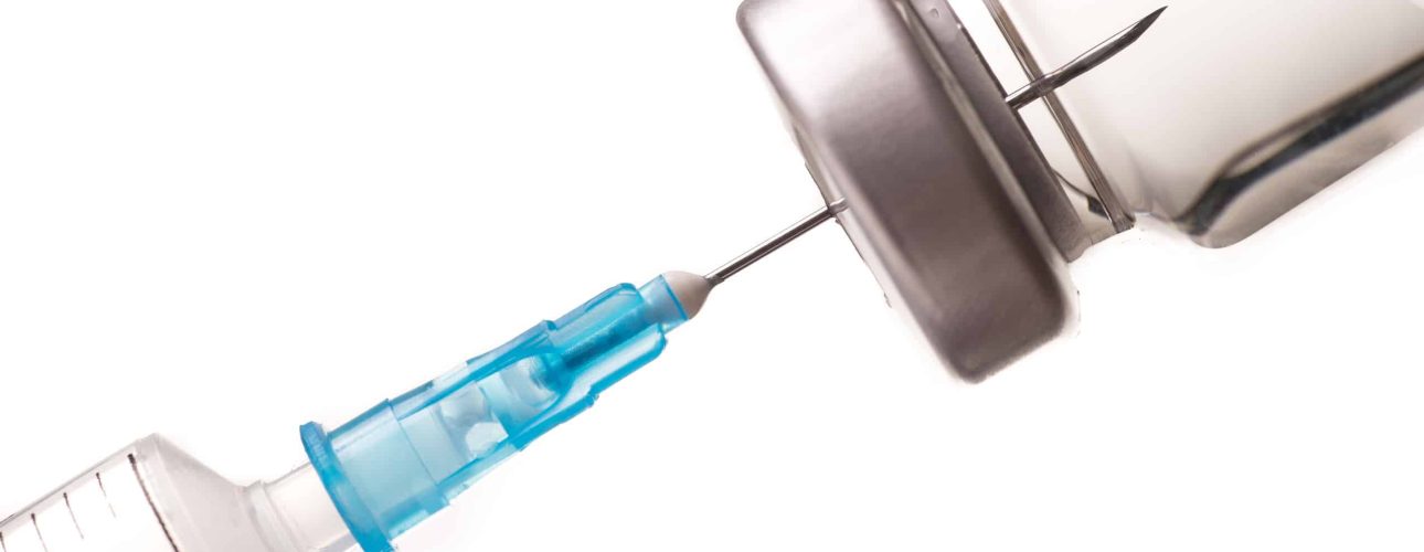 Syringe, needle and medicine vial. The needle sticks through the sterile membrane into the clear liquid.