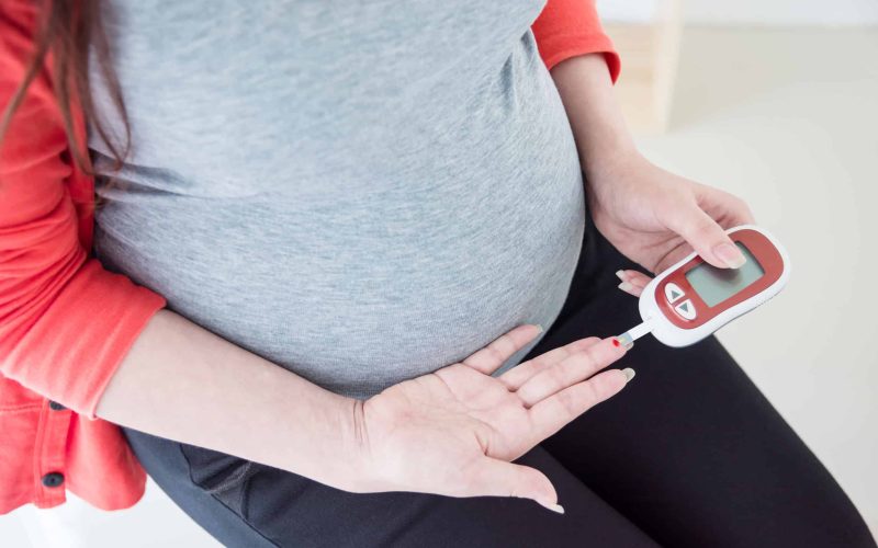 Pregnant woman checking blood sugar by herself at home