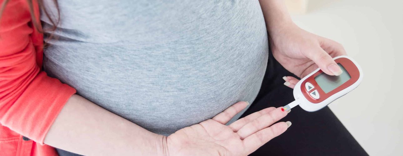 Pregnant woman checking blood sugar by herself at home