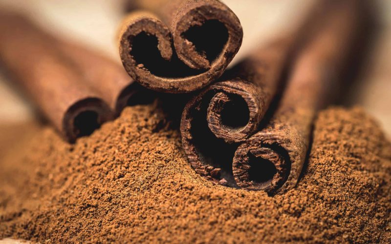 Cinnamon sticks with cinnamon powder on wooden background,