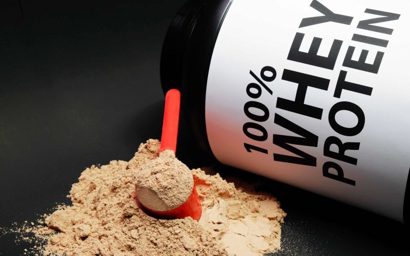 Whey Protein Powder in measuring scoop. Bodybuilding Nutrition Supplements.