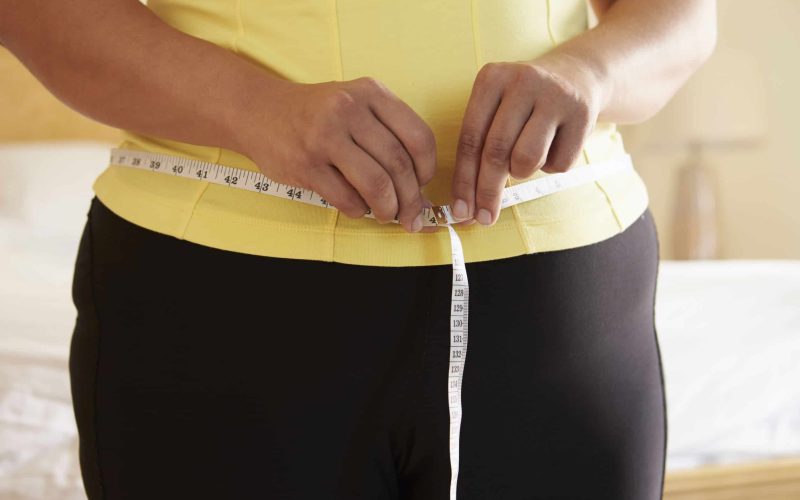 Close Up Of Overweight Woman Measuring Waist