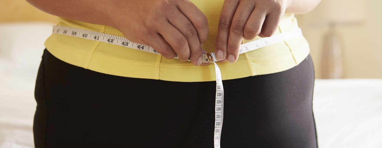 Close Up Of Overweight Woman Measuring Waist