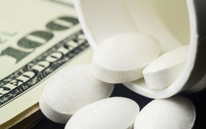 White pills of calcium, vitamin supplement, medical tablets in bottle on dollar banknote, macro image.