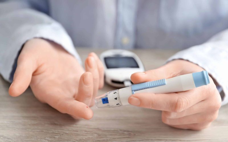 Woman using lancet pen, closeup. Diabetes monitoring