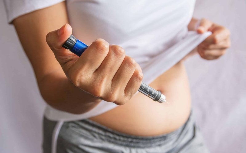 Diabetes concept insulin syringe injection shot into abdomen